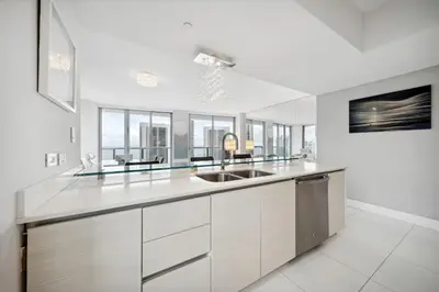a white kitchen with a sink and some windows at Million Dollar Waterfront Penthouse in Hallandale Beach