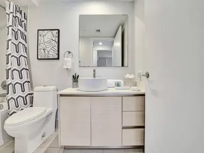 a bathroom with a sink and a toilet and a mirror at Luxury Waterfront Suite in Hallandale Beach