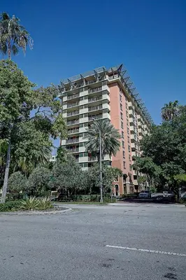 a large pink building with palm trees in a parking lot at Coconut Grove Beauty 1 bedroom Bayview Condo with Free Parking in Miami