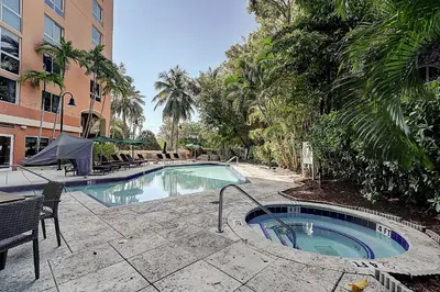 a swimming pool with a table and chairs next to a building at Coconut Grove Beauty 1 bedroom Bayview Condo with Free Parking in Miami