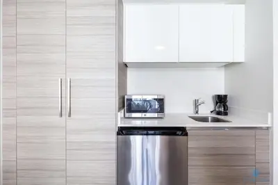 a kitchen with white cabinets and a stainless steel refrigerator at Hollywood Bliss Studio Balcony Beach View in Hollywood