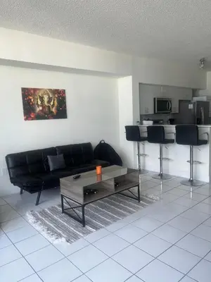 a living room with a black couch and a table at Enjoy an endless summer - Parking included! in Sunny Isles Beach