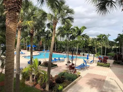 a resort swimming pool with palm trees and chairs at Enjoy an endless summer - Parking included! in Sunny Isles Beach