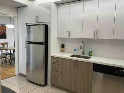 a kitchen with white cabinets and a stainless steel refrigerator at 7th FL Ocean view spacious 1 bedroom in Hollywood