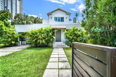 a white house with a fence in front of a yard at Stunning Home LifeStyle Miami in Miami