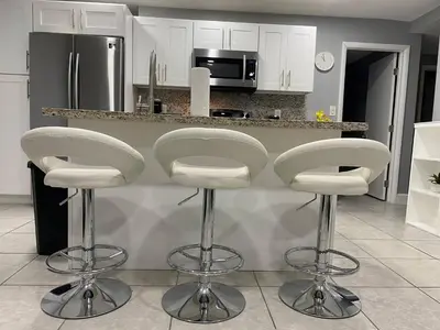 a kitchen with two white bar stools in front of a counter at Executive Luxury Suite in Fort Lauderdale