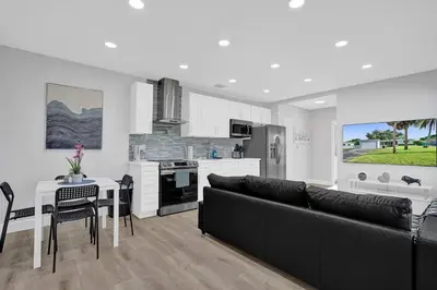 a living room with a black couch and a kitchen at The Front Wave Luxury Home in Fort Lauderdale