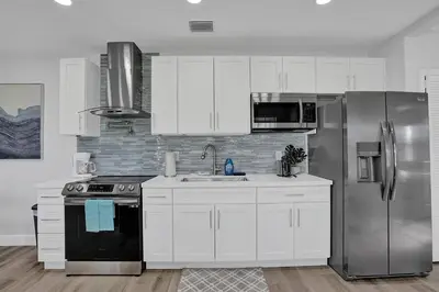 a kitchen with white cabinets and a stainless steel refrigerator at The Front Wave Luxury Home in Fort Lauderdale