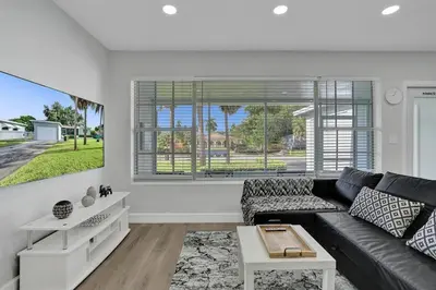 a living room with a black couch and a window at The Front Wave Luxury Home in Fort Lauderdale