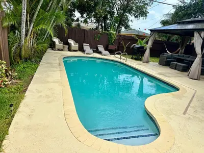 a swimming pool with chairs in a yard at Pool house 3 bedroom 2 bathroom in North Miami Beach
