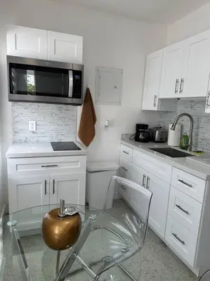 a white kitchen with a chair and a microwave at Villa Clara Gold-Little Havana in Miami