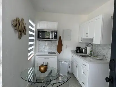 a small white kitchen with a glass table in it at Villa Clara Gold-Little Havana in Miami