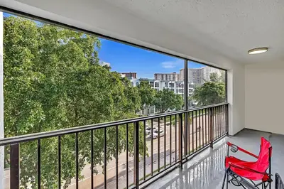 a red chair sitting on a balcony with a view at One Bedroom Steps Away From The Beach! in Sunny Isles Beach
