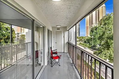 a red chair sitting on a balcony with windows at One Bedroom Steps Away From The Beach! in Sunny Isles Beach