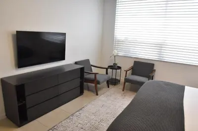 a living room with a flat screen tv and two chairs at 515-Trendy 2Bd2Ba Midtown HUGE private patio! in Miami