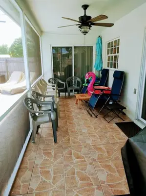 a screened in porch with chairs and a ceiling fan at Amazing 5 Bedroom Pool Home - Minimum 28 days Stay Only Great Location! in Miramar