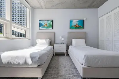 two beds in a white room with two windows at 516-2Bd2Ba Midblock Apartment FREE parking in Miami
