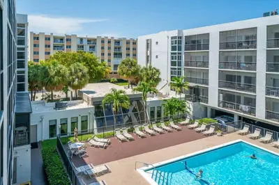 an apartment patio with a pool and chairs and buildings at Enjoy Fully Equipped 2BR Condo Near The Beach in Sunny Isles Beach