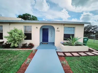 a house with a blue door in a yard at Walk to Hard Rock ~ Amazing 5 Star Home Away From Home! in Miami Gardens