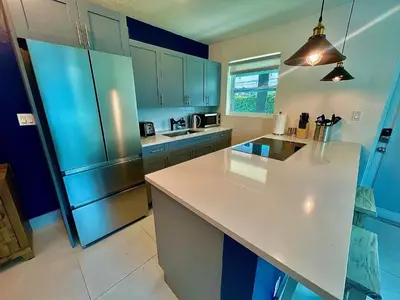 a kitchen with a white counter and a refrigerator at MiamiVice Las Olas Near Beach and Park w Fire Pit in Fort Lauderdale