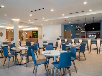 a dining room with tables and blue chairs at EVEN Hotel Miami - Doral Area by IHG in Sweetwater