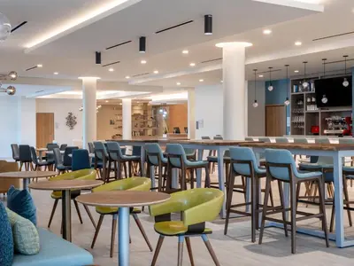 a cafeteria with tables and chairs and a bar at EVEN Hotel Miami - Doral Area by IHG in Sweetwater