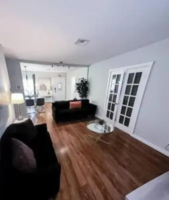 a living room with a black couch and wooden floors at Charming 4BR Home with Heated Pool in Hollywood in Hollywood