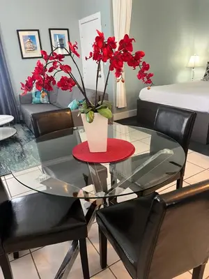 a room with a glass table with a vase with red flowers at Ocean Breeze Studio With Parking By The Beach in Miami Beach