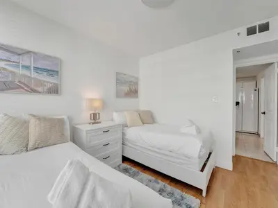 a white bedroom with two beds and a dresser at High floor 2BD with beach service 1608 in Miami Beach