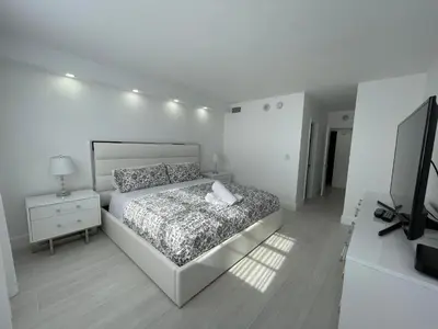 a white bedroom with a bed and a television at Amazing Ocean View! 10 floor Parking included in Sunny Isles Beach