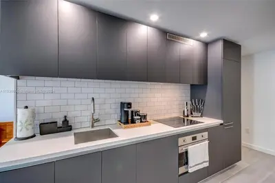 a kitchen with black cabinets and a counter top at Ocean View Designer Studio, Pool in Miami
