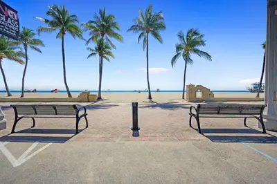 two benches in front of a beach with palm trees at Apartamento justo en la playa in Hollywood