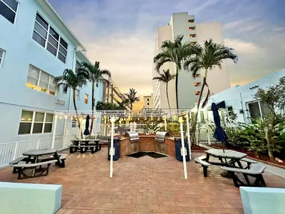 a patio with benches and palm trees in front of a building at Apartamento justo en la playa in Hollywood