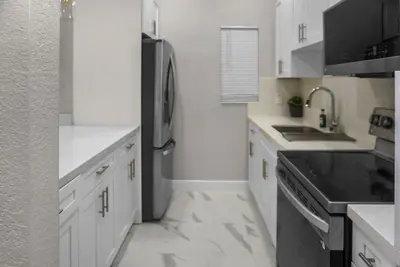 a kitchen with white cabinets and a black refrigerator at Miami Luxury Home Rental in Miami