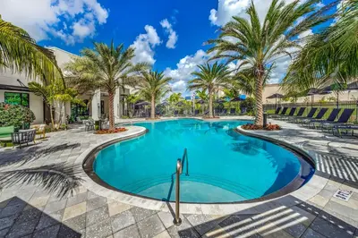 a swimming pool with palm trees in a resort at 1 Mi to Hard Rock Stadium! Chic Retreat with Pool in Joe Robbie Stadium Heliport