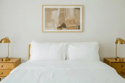 a bedroom with a white bed with two lamps at Hard Rock Stadium Home Base! Luxe Condo with Pool in Joe Robbie Stadium Heliport