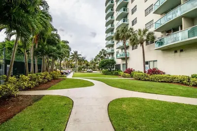 a walkway in front of a building with palm trees at Beautiful holiday apartment in Ocean Recerve near beach in Sunny Isles Beach