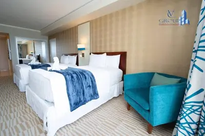 a hotel room with three beds and a blue chair at Luxurious beachfront studio in Sunny Isles Beach