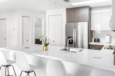 a kitchen with a large white counter with white chairs at Biscayne Park Villas 15450 in Miami