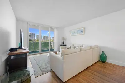 a living room with a white couch and a television at Nice and economic family apartment on the beach in Sunny Isles Beach