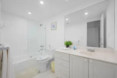 a white bathroom with a tub and a sink and a toilet at Nice and economic family apartment on the beach in Sunny Isles Beach