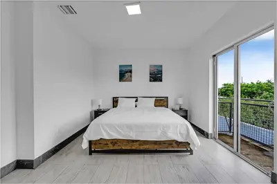 a white bedroom with a bed and a large window at Biscayne Park Villas 15440 in Miami