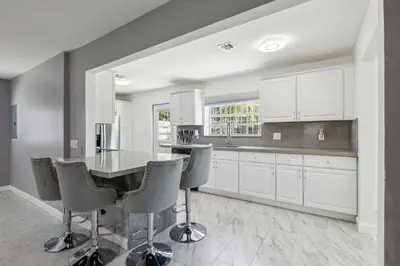 a kitchen with white cabinets and a table and chairs at Spacious 3BR Villa in Miami with Fenced Backyard in Miami