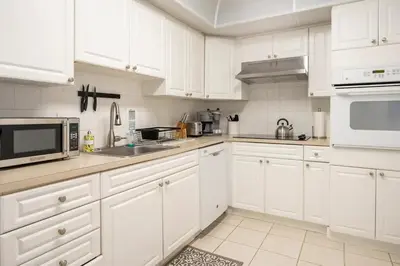 a white kitchen with white cabinets and appliances at Beachfront, Pools, Patio, King Bd Villa- Hollywood FL in Hollywood
