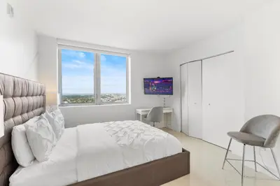 a white bedroom with a bed and a window at Spacious Luxury Apartment at Beachwalk Resort with Ocean Views and Private Foyer in Hallandale Beach