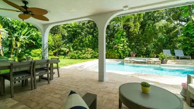 a patio with a table and chairs and a swimming pool at Villa Viscayne - Miami Modern Luxury with Pool & Spa in Biscayne Park