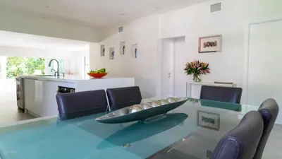a dining room with a glass table and blue chairs at Villa Viscayne - Miami Modern Luxury with Pool & Spa in Biscayne Park