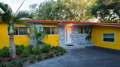 a yellow house with a palm tree in front of it at Villa Tropical - Your private Miami Resort with a heated pool in North Miami