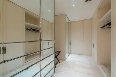 a walk in closet with glass cabinets and a mirror at 3MM Oceanfront Residence at Finest Bal Harbour Resort - Hotel Amenities in Miami Beach