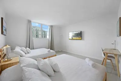 a white room with three beds and a window at Beautiful and big Apartment by the beach in Sunny Isles Beach